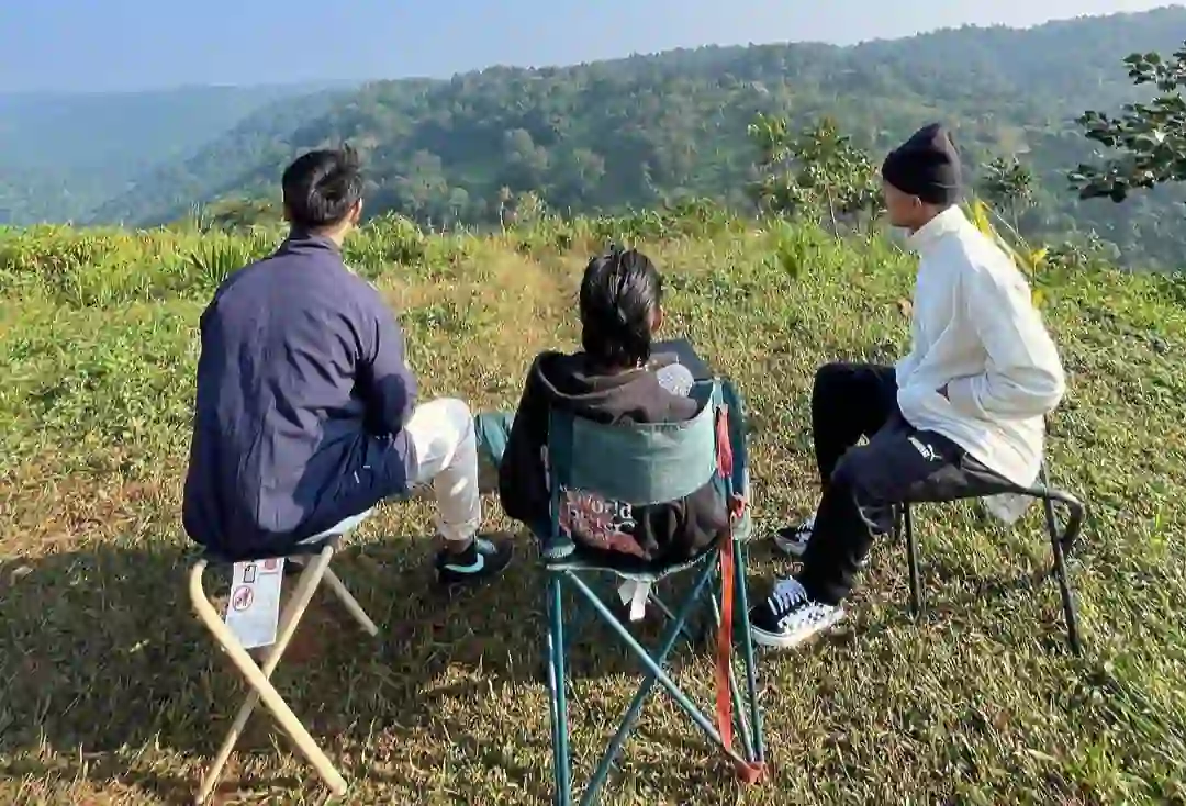 A group of three peoples sitting on the camping chairs on a mountain