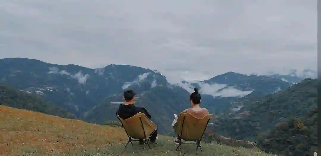 A couple sitting on the camping chair looking at the sceneries