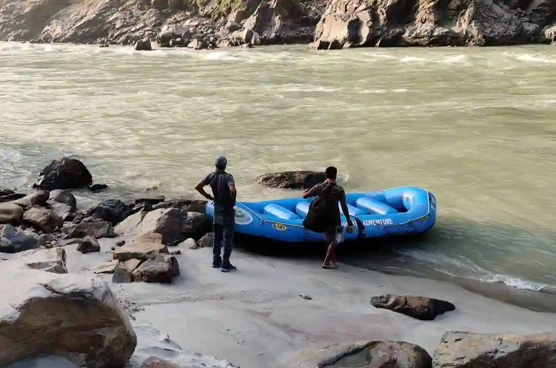 Two people preparing for a rafting trip beside the river Ganga