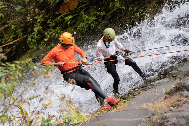 A couple trying rappelling to reach the river from a cliff