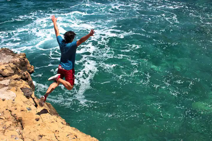 A man jumping from a cliff in the river