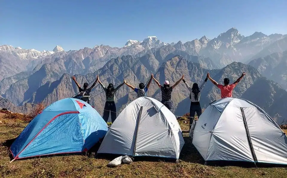 Three camps in Auli with people standing on the cliff