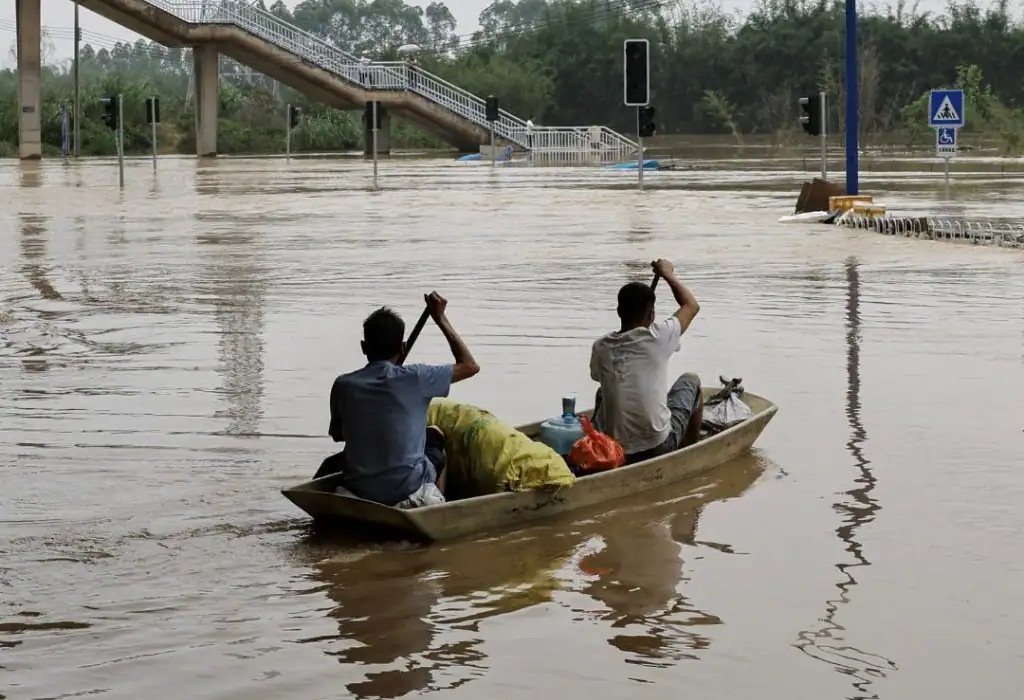 Two people rowing a boat in flooded area